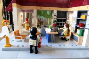 A colleague of my brown-haired main character tells her how he overheard what the red-head said. The colleague has his name taped on his back as the other characters do. That way, they don't get mixed up with each other.